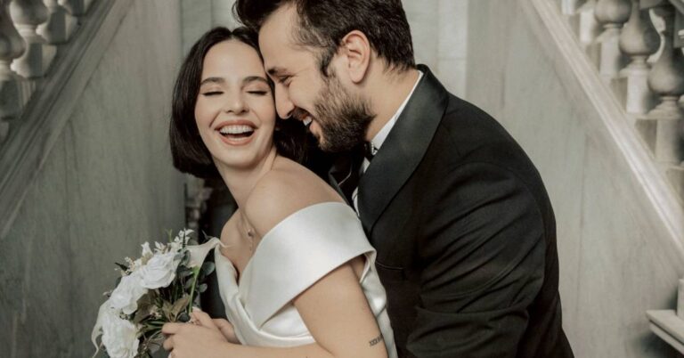 a newlywed couple are hugging on the stairs of their wedding venue 4x3